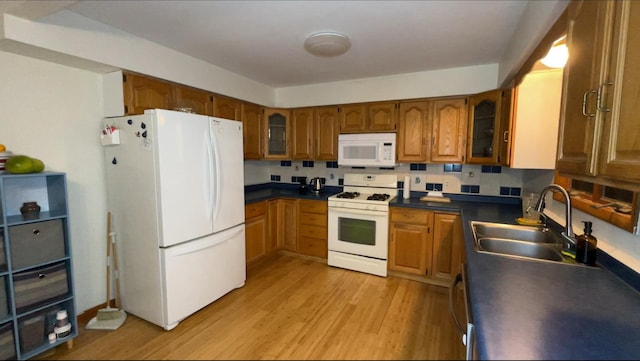 kitchen with light wood-type flooring, white appliances, sink, and tasteful backsplash