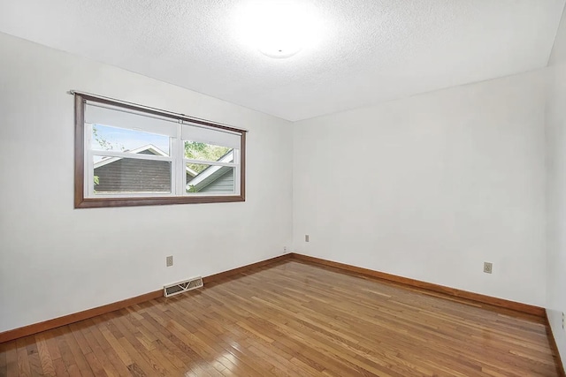 spare room featuring wood-type flooring and a textured ceiling