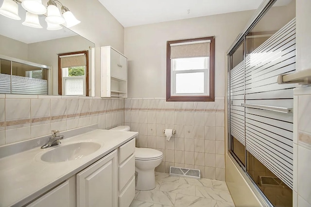 full bathroom with vanity, toilet, shower / bath combination with glass door, and tile walls