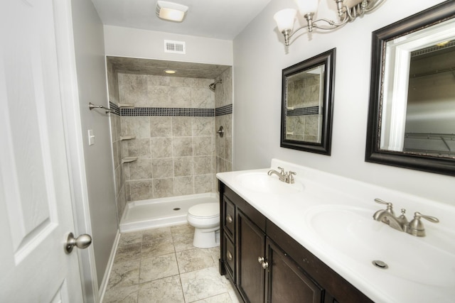 bathroom with vanity, toilet, and tiled shower