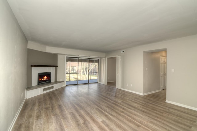 unfurnished living room with hardwood / wood-style flooring and a tiled fireplace