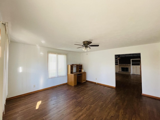 unfurnished living room with dark hardwood / wood-style flooring, a brick fireplace, and ceiling fan