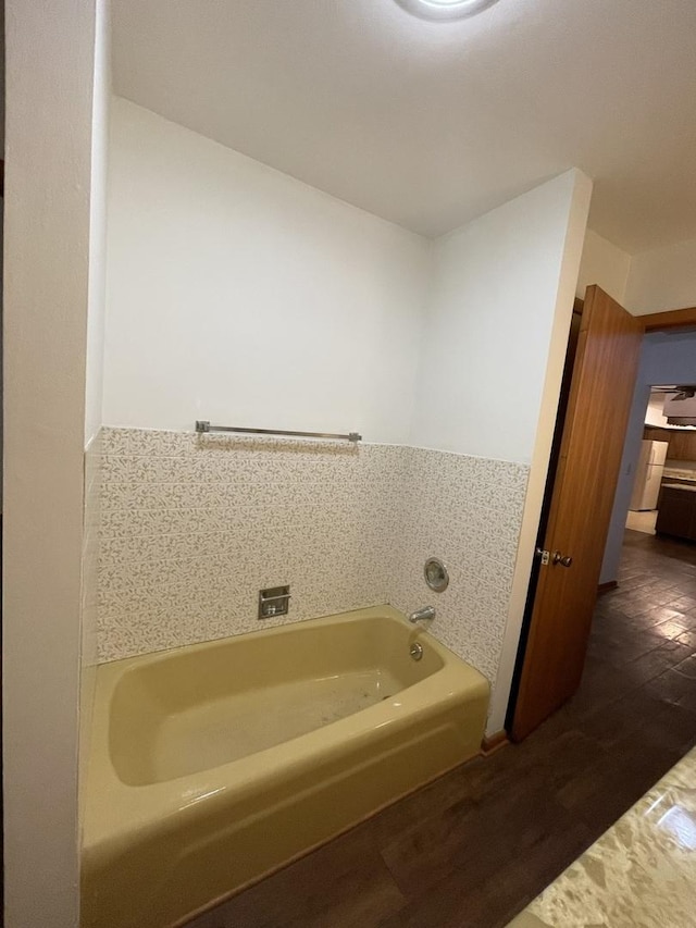 bathroom with wood-type flooring, a bathtub, and tile walls