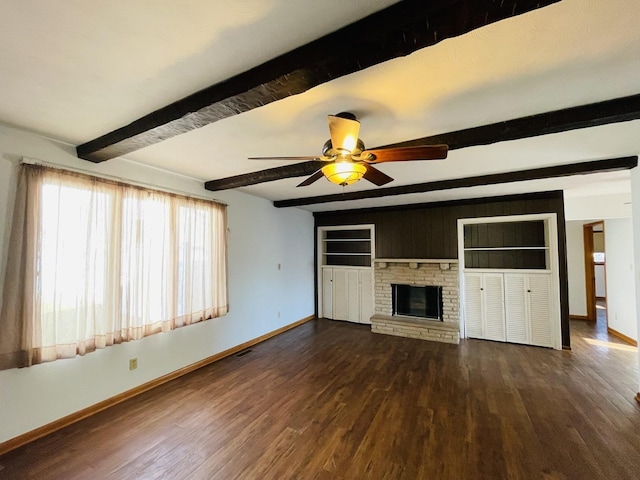 unfurnished living room with beamed ceiling, ceiling fan, dark wood-type flooring, and a brick fireplace