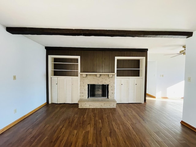 unfurnished living room with dark hardwood / wood-style flooring, a brick fireplace, ceiling fan, beam ceiling, and built in features