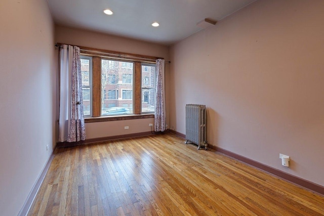 unfurnished room featuring radiator heating unit and light wood-type flooring