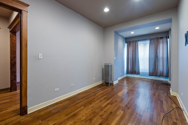 unfurnished room featuring radiator and dark hardwood / wood-style floors