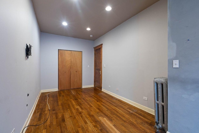 unfurnished bedroom featuring radiator heating unit, dark wood-type flooring, and a closet