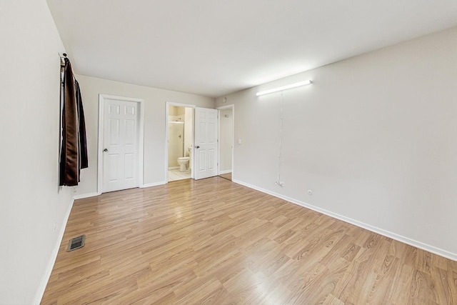 unfurnished bedroom featuring light hardwood / wood-style floors and connected bathroom