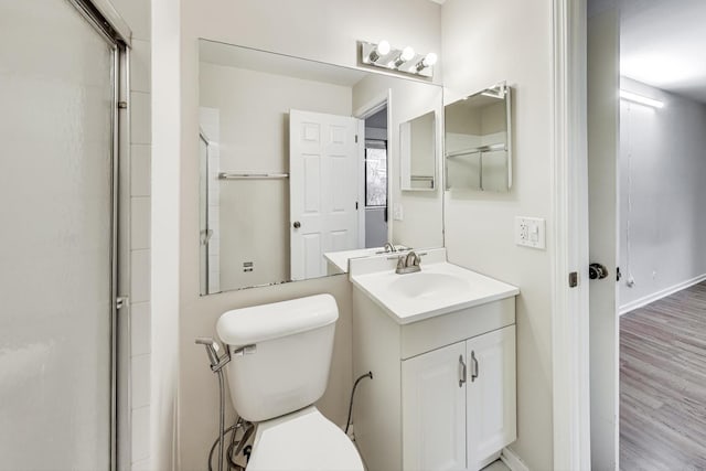 bathroom with hardwood / wood-style floors, vanity, toilet, and a shower with door