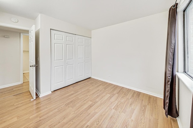 unfurnished bedroom with light wood-type flooring and a closet