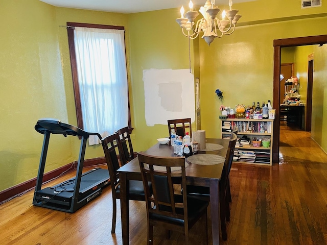 dining space with hardwood / wood-style floors and a notable chandelier