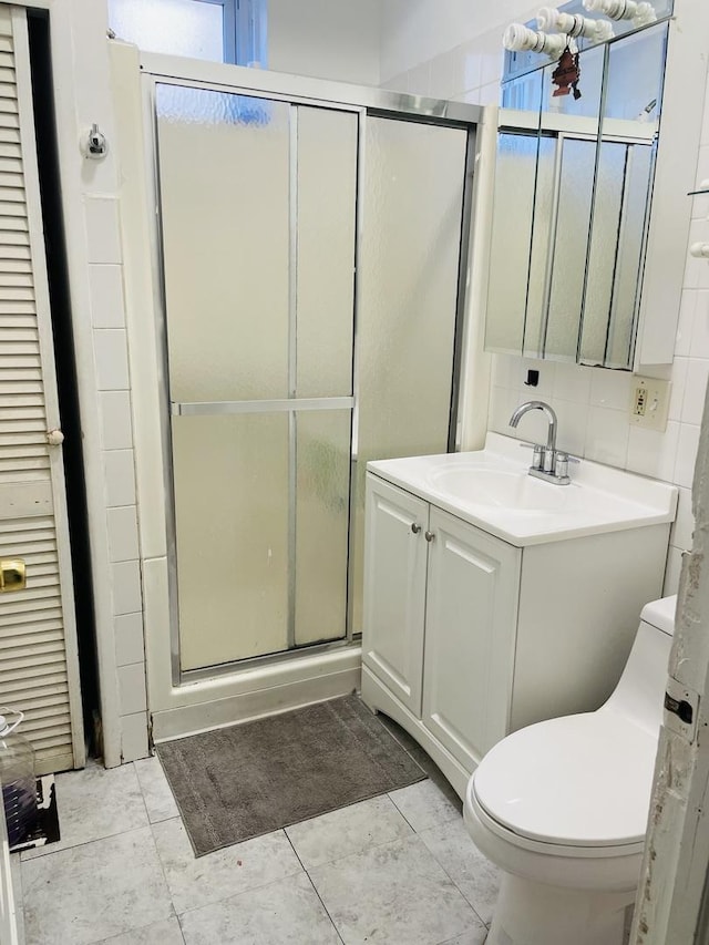 bathroom with tile patterned flooring, toilet, decorative backsplash, a shower with door, and vanity