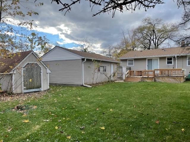 back of house with a shed, a yard, and a wooden deck