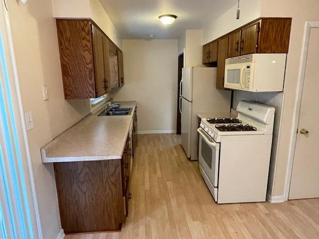 kitchen featuring white appliances, sink, and light hardwood / wood-style flooring