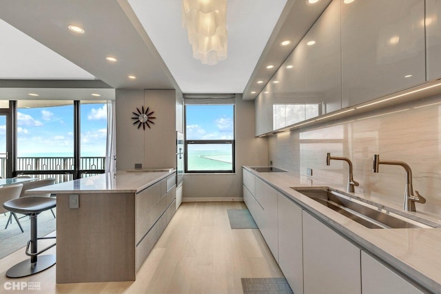 kitchen featuring light stone countertops, sink, a water view, and a healthy amount of sunlight