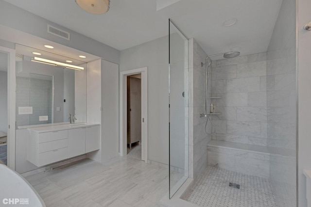 bathroom featuring a tile shower and vanity