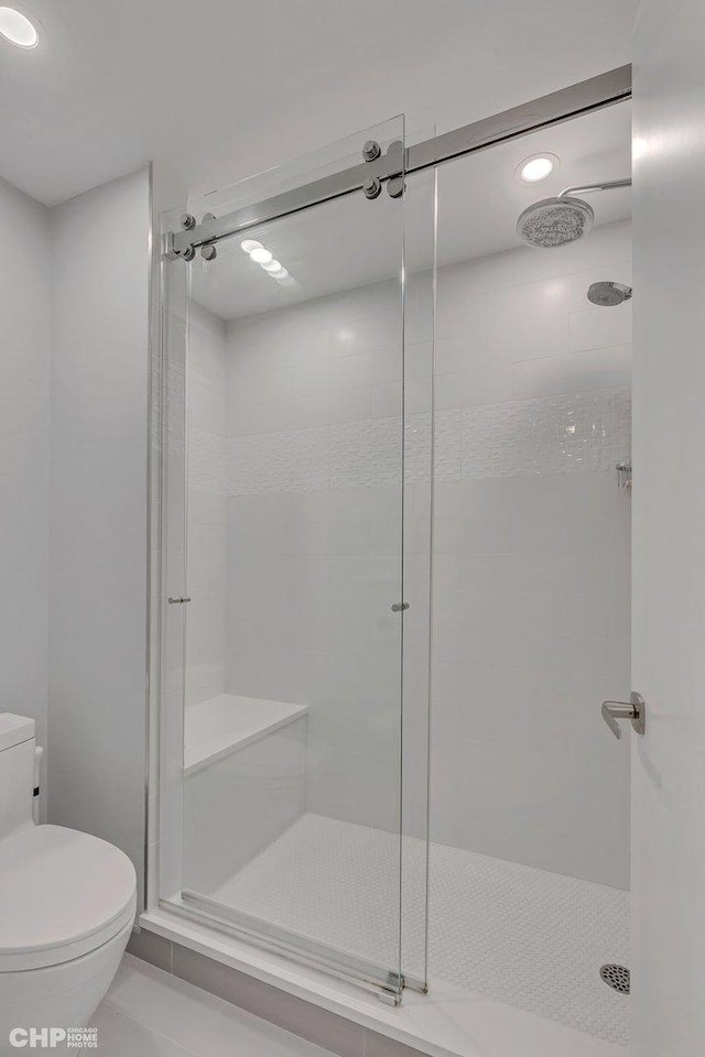 bathroom with tile patterned floors, a shower with shower door, and toilet