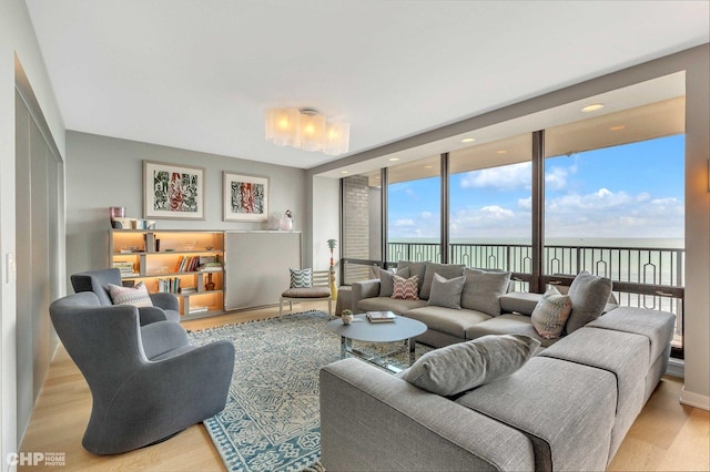 living room featuring light wood-type flooring, a water view, and expansive windows