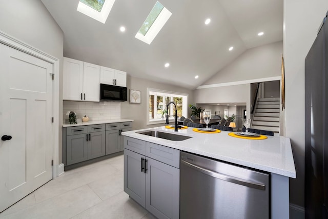 kitchen with tasteful backsplash, sink, light tile patterned floors, dishwasher, and white cabinetry