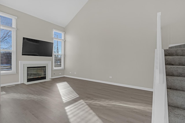 unfurnished living room with high vaulted ceiling, hardwood / wood-style flooring, and a tile fireplace