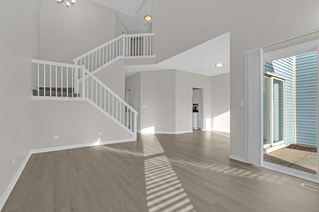 unfurnished living room with hardwood / wood-style flooring and a towering ceiling