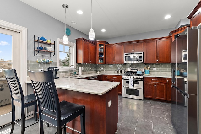 kitchen with hanging light fixtures, tasteful backsplash, kitchen peninsula, a kitchen bar, and appliances with stainless steel finishes