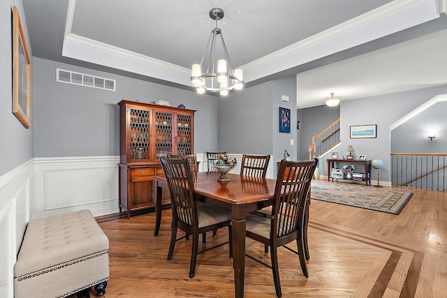 dining space with a notable chandelier, a raised ceiling, and crown molding