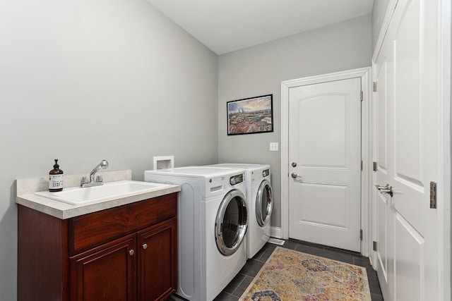 laundry room featuring washer and dryer, dark tile patterned floors, and sink