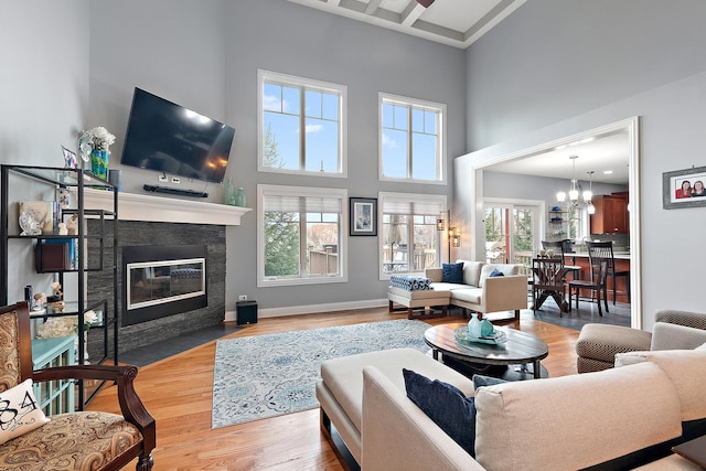 living room with a chandelier, a high ceiling, light hardwood / wood-style flooring, and a healthy amount of sunlight