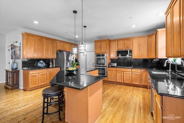 kitchen featuring sink, hanging light fixtures, a center island, stainless steel appliances, and light hardwood / wood-style flooring