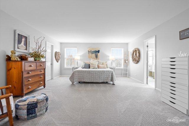 bedroom with multiple windows, connected bathroom, and light colored carpet