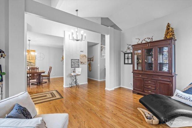 living room featuring lofted ceiling, light hardwood / wood-style flooring, and a chandelier