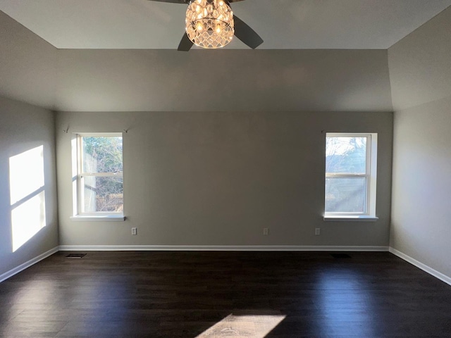 spare room featuring dark wood-type flooring, vaulted ceiling, ceiling fan, and a healthy amount of sunlight