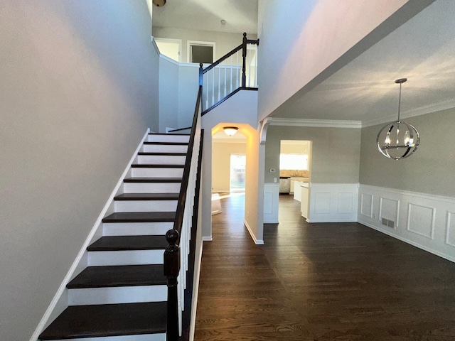 stairway with hardwood / wood-style floors, a notable chandelier, and ornamental molding