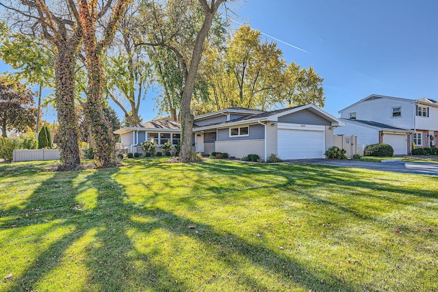 view of front facade featuring a garage, aphalt driveway, fence, and a front lawn