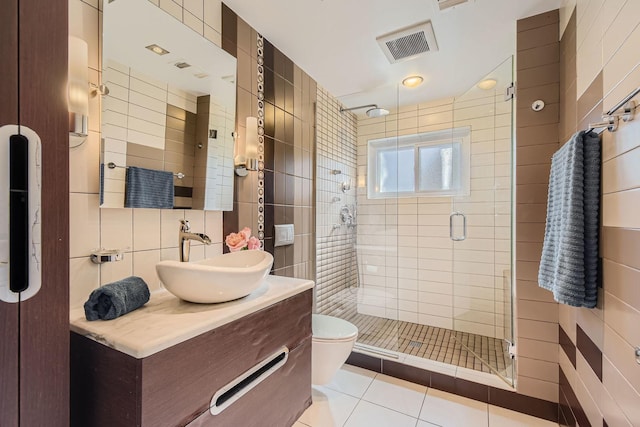 full bath with a stall shower, visible vents, tile patterned floors, vanity, and tile walls