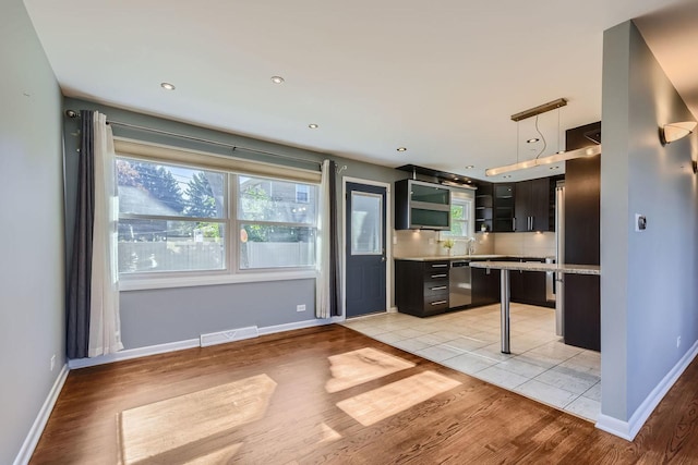 kitchen with light countertops, light wood-type flooring, visible vents, and baseboards