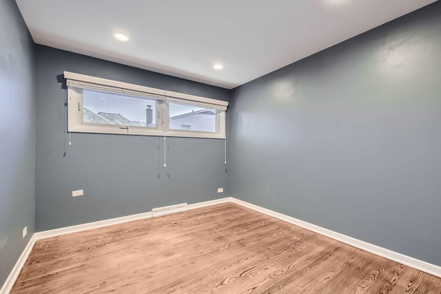 empty room with baseboards, wood finished floors, and recessed lighting