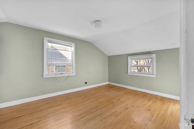 additional living space with a healthy amount of sunlight, vaulted ceiling, and light hardwood / wood-style floors