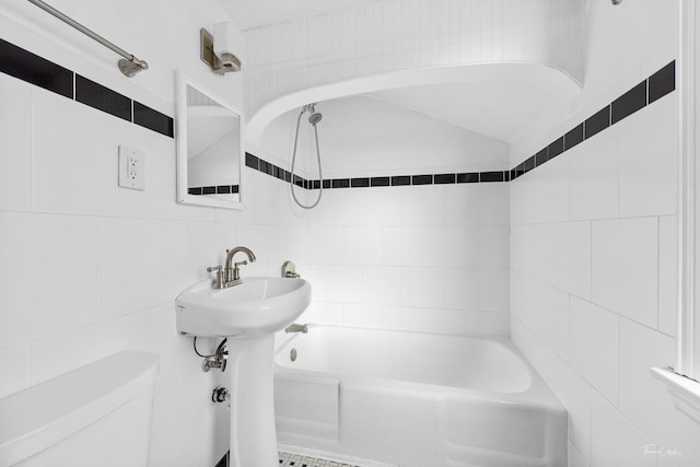 bathroom featuring toilet, tile walls, and tiled shower / bath