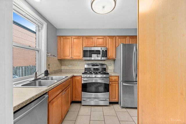 kitchen featuring sink, light stone counters, decorative backsplash, light tile patterned floors, and appliances with stainless steel finishes