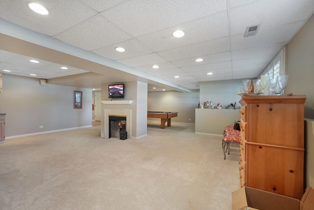 basement with a paneled ceiling and light carpet