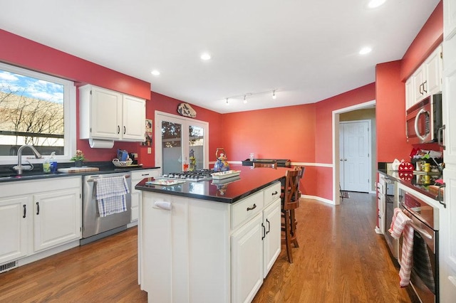 kitchen featuring sink, stainless steel appliances, a center island, and white cabinets