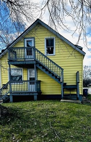 rear view of property featuring a lawn and a balcony