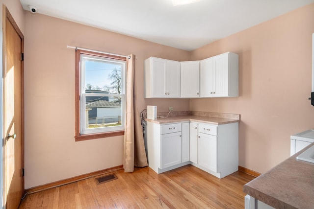 kitchen with light hardwood / wood-style flooring and white cabinets