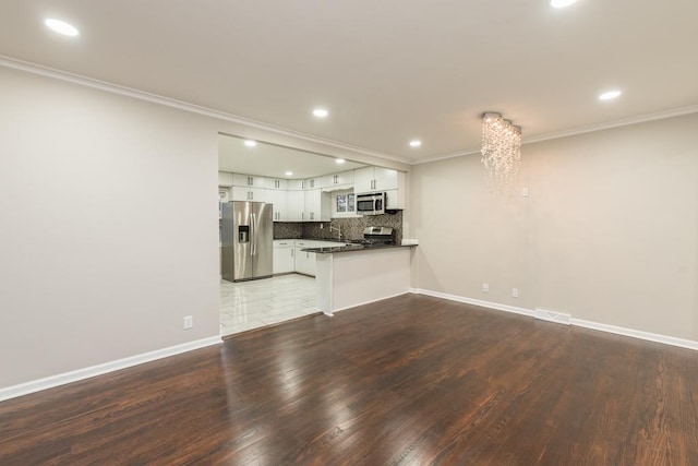 unfurnished living room featuring dark hardwood / wood-style floors, ornamental molding, and a notable chandelier