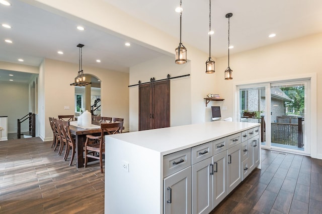 kitchen with pendant lighting, a barn door, a center island, and dark wood-type flooring