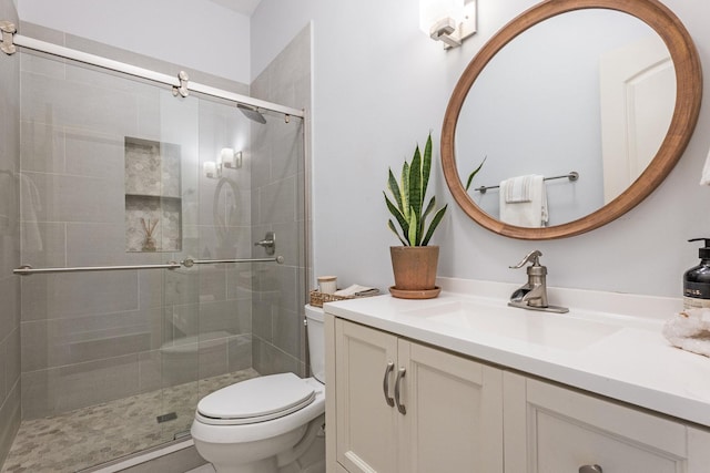 bathroom featuring vanity, a shower with shower door, and toilet