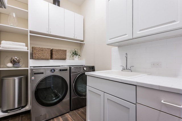 washroom with cabinets, dark hardwood / wood-style floors, washing machine and dryer, and sink